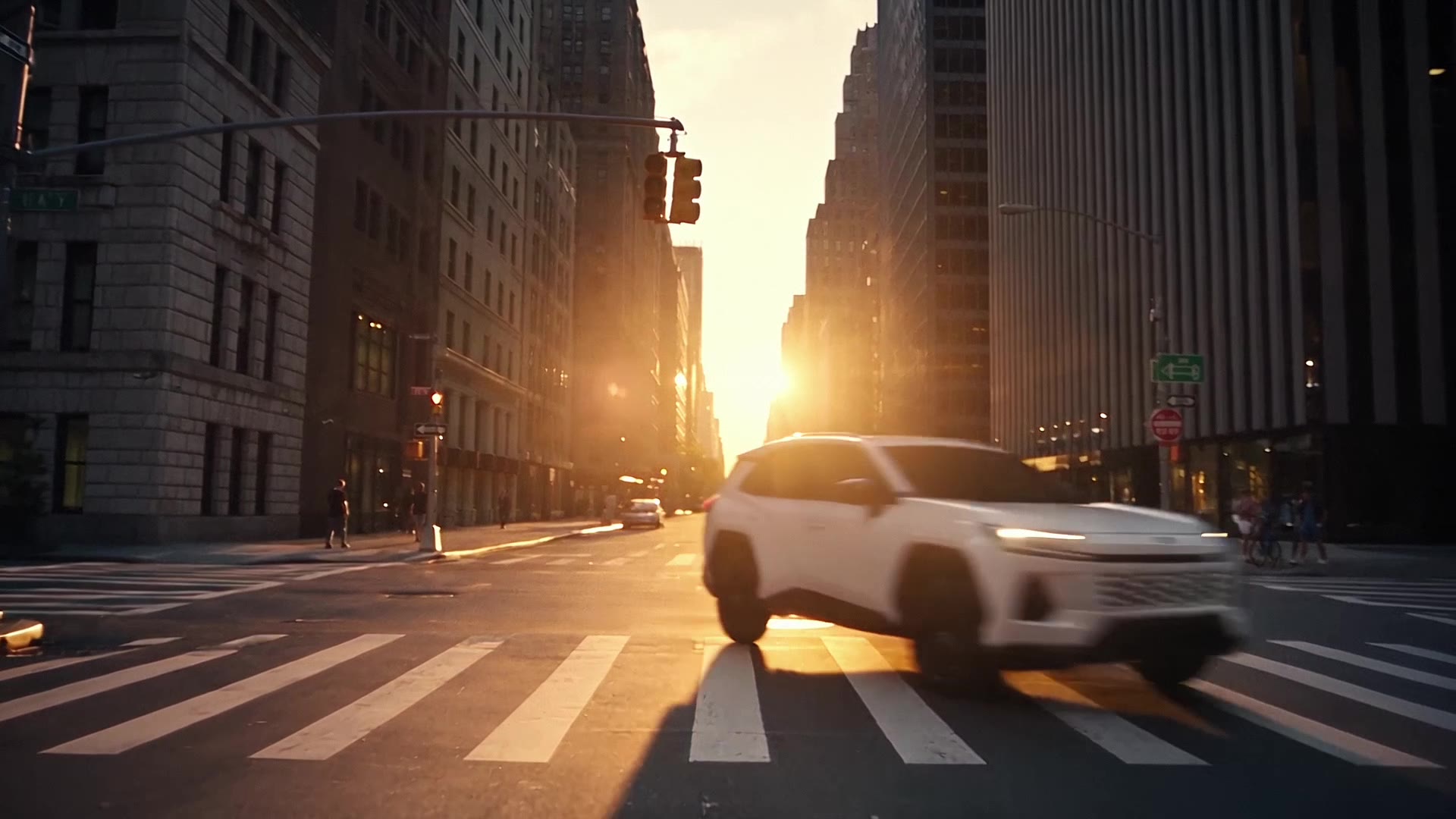 White Toyota RAV4 crossing a Manhattan intersection at sunrise